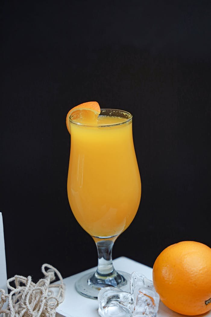 A glass of orange juice with a slice of orange on top